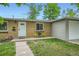 Inviting exterior of a brick home with a well-manicured lawn and cheerful yellow chairs on the front porch at 5820 S Cherokee St, Littleton, CO 80120