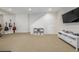 Open finished basement with neutral carpet, white shelving, and a mounted television at 3433 N Wabash St, Denver, CO 80238
