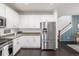 Bright kitchen with white cabinets, stainless steel fridge, and an adjacent staircase at 3433 N Wabash St, Denver, CO 80238
