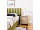 Bedroom with a green upholstered bed and a light wood nightstand at 1836 Grove St # 107, Denver, CO 80204
