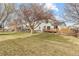 Spacious backyard with lush grass, wooden fence, mature trees, and a deck, providing privacy and outdoor enjoyment at 1189 Fall River Cir, Longmont, CO 80504