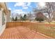 Wood deck with backyard views of mature trees under bright blue skies at 1189 Fall River Cir, Longmont, CO 80504