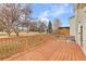 Wood deck with backyard views of trees and blue skies with fluffy white clouds at 1189 Fall River Cir, Longmont, CO 80504
