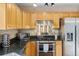 Close-up on kitchen appliances including gas range, microwave and fridge with wood cabinets at 1189 Fall River Cir, Longmont, CO 80504