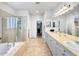 Large bathroom with double sinks, a soaking tub, a glass-enclosed shower, and walk in closet at 7722 E 6Th Pl, Denver, CO 80230