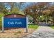 View of the Oak Park sign with a playground and lush greenery in the background on a sunny day at 10868 W 70Th Ave, Arvada, CO 80004