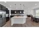 Modern kitchen with an island, stainless steel appliances, dark cabinets, and an adjacent dining area at 5045 Preserve Pl, Firestone, CO 80504