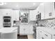 Modern kitchen featuring white cabinets, stainless steel appliances, and mosaic backsplash at 21062 E Mansfield Pl, Aurora, CO 80013