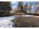 Large fenced backyard featuring mature trees and a partially snow-covered lawn at 4638 S Mobile Way, Aurora, CO 80015