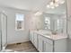 Bright bathroom with double sinks, white cabinets, a large mirror, and a shower with glass doors at 9062 Telluride Ct, Commerce City, CO 80022