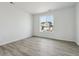 Bright, empty bedroom featuring wood-look flooring, neutral walls, and a large window for ample natural light at 9062 Telluride Ct, Commerce City, CO 80022