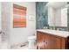 A modern powder bath features unique green tile accent wall, bamboo shade and wood vanity at 4960 Malaya St, Denver, CO 80249