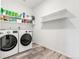 A well-lit laundry room featuring a side-by-side washer and dryer and open shelving at 4960 Malaya St, Denver, CO 80249