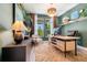 Stylish home office featuring wood desk and dark green accent wall with large windows and decorative shelving at 4960 Malaya St, Denver, CO 80249