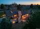 Aerial view of a well-lit home featuring balconies, a stone chimney, and lush surrounding greenery at 9745 Derby Way, Parker, CO 80134