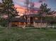 Inviting two-story home with a well-manicured lawn, mature trees, and warm exterior lighting at 9745 Derby Way, Parker, CO 80134