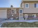 Close up of the front door and address of this split-level home with brick exterior and front yard bench at 11002 E Ohio Pl, Aurora, CO 80012