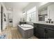 A stylish bathroom features double vanities, a soaking tub with tile surround, and a glass-enclosed shower at 8985 Chalk Creek Pl, Littleton, CO 80125