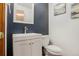 Stylish half-bathroom featuring a modern vanity, toilet, and a blue accent wall at 5457 S Valdai St, Aurora, CO 80015