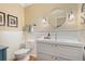 Powder room features a white vanity, a round mirror, sconce lighting, and paneling at 7770 S Ivy Way, Centennial, CO 80112