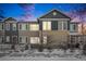 Two-story townhouse exterior with snowy yard and walkway at dusk at 15550 W 64Th Pl # D, Arvada, CO 80007