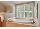 Relaxing bathroom shows large soaking tub with shuttered window and warm tile surround at 4545 S Monaco St # 114, Denver, CO 80237