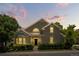 Charming home showcasing lush landscaping, gray siding, gabled roof, and a well-manicured lawn at dusk at 4545 S Monaco St # 114, Denver, CO 80237