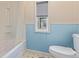 A well-lit bathroom with a tub, a window, a toilet, and blue paneling for a clean and bright space at 8400 Adams Way, Denver, CO 80229