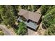 Stunning aerial view of a brown chalet-style home surrounded by lush green trees and a spacious deck at 11760 Baca Rd, Conifer, CO 80433