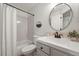 Bright bathroom with a shower-tub combo, sleek white fixtures and modern round mirror at 5554 S Ward Way, Littleton, CO 80127