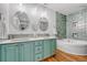 Bright, updated bathroom with dual sinks, mirrors, and green tiled tub at 11820 W 66Th Pl # C, Arvada, CO 80004