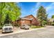 Exterior view of townhouse with wood siding and brick accents, surrounded by lush landscaping and parking at 11820 W 66Th Pl # C, Arvada, CO 80004