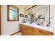 Bathroom featuring a wood vanity, large mirror, and window providing natural light and a charming aesthetic at 10346 E Crestridge Ln, Englewood, CO 80111