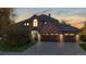 Charming brick home featuring an attached three-car garage and lush landscaping at dusk at 10346 E Crestridge Ln, Englewood, CO 80111