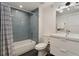 Bathroom with blue-tiled shower and a white vanity and toilet with modern light fixtures at 1675 S Steele St, Denver, CO 80210