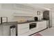White kitchenette with stainless steel appliances, decorative floating shelves, and a grey countertop at 1675 S Steele St, Denver, CO 80210
