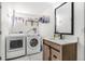 Bright laundry room featuring front load washer, dryer, sink with vanity, and stylish storage shelves at 9093 Dudley St, Westminster, CO 80021