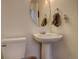 A simple powder room with a pedestal sink, toilet, and round mirror at 11020 Glacier Park Cir, Parker, CO 80138