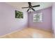 Simple purple bedroom with a light wood floor, ceiling fan, and a window with blinds at 13960 Grape St, Thornton, CO 80602
