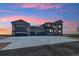 Large home exterior featuring a massive driveway, multi-car garage, and neutral paint scheme during sunset at 2990 S Juliet Ct, Strasburg, CO 80136