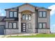 Gorgeous two-story home with a stone pillar entrance, black framed windows, and manicured lawn at 2990 S Juliet Ct, Strasburg, CO 80136