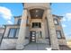 Elegant stone pillar entrance with modern front door and large black framed windows at 2990 S Juliet Ct, Strasburg, CO 80136