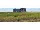 Oversized lot with weeds and sparse vegetation with an expansive custom home in the background at 2990 S Juliet Ct, Strasburg, CO 80136