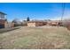 Wide shot of a large grassy backyard with a brick house, wooden fences, and mature trees at 16805 W 16Th Pl, Golden, CO 80401
