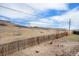 Spacious backyard with a hill view, wooden fence, and dry vegetation under a bright sky at 16805 W 16Th Pl, Golden, CO 80401