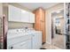 Bright laundry room featuring white washer/dryer, wooden cabinets, and tile flooring at 16805 W 16Th Pl, Golden, CO 80401