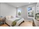 Cozy bedroom featuring a queen bed, hardwood floors, neutral decor, and ample natural light from two windows at 423 Rogers Way, Castle Rock, CO 80104