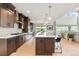 Modern kitchen boasts dark cabinets, an island with seating, pendant lights, and stainless steel appliances at 423 Rogers Way, Castle Rock, CO 80104