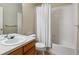 Bathroom with wood vanity, white countertop, bathtub and shower with white shower curtain at 13756 Legend Trl # 101, Broomfield, CO 80023