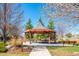 Community gazebo on a concrete pad with wooden benches and tables surrounded by green grass and walking path at 10510 Berthoud Way, Parker, CO 80134